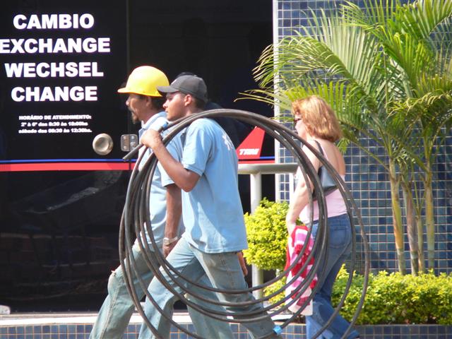Workers carrying pipe on shoulder